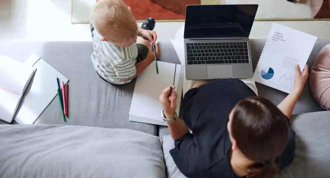 Mama pracująca na kanapie z dzieckiem obok
